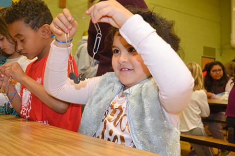A young Cena y Ciencias visitor has magnets attached to her paperclip chain.