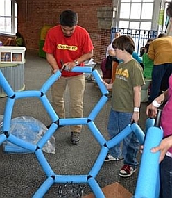 Museum visitors putting together the Giant C60 Buckyball with the help of a MRSEC activity leader.